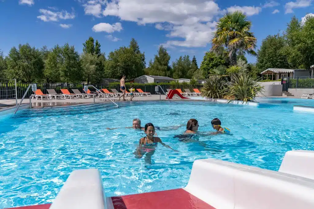 Piscine extérieure avec transats et toboggan rouge.