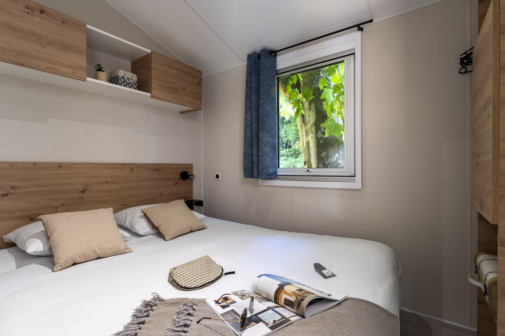 Chambre lumineuse avec lit et vue sur jardin.