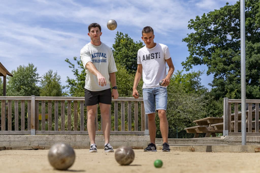 Deux hommes jouant à la pétanque en extérieur.
