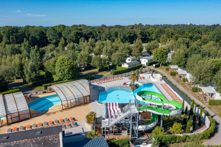 Parc aquatique avec toboggans verts et piscine couverte.