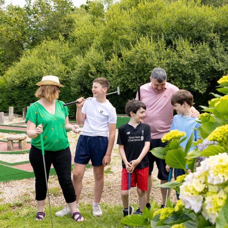 Famille jouant au mini-golf en plein air.
