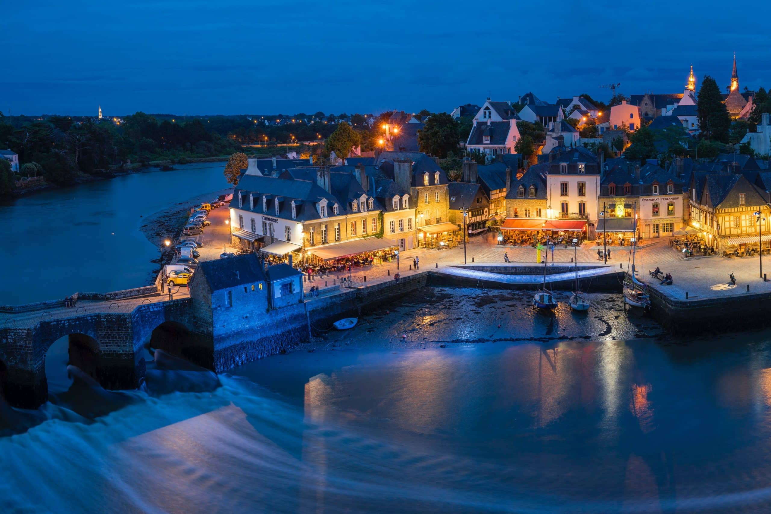 Ville bretonne illuminée au bord de la rivière.
